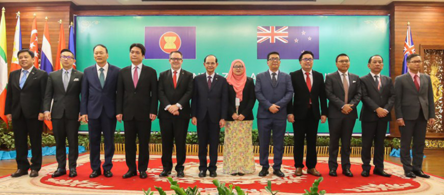 Group of people in suits, posed in front of country flags including ASEAN and New Zealand.